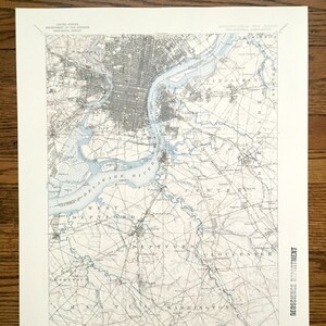 Könnte beinhalten: Eine historische topografische Karte von Philadelphia, Pennsylvania, und den umliegenden Gebieten, einschließlich Teilen von New Jersey. Die Karte zeigt detaillierte Straßenraster, Wasserwege und geografische Merkmale, gedruckt in Grau- und Blautönen. Die Karte trägt die Aufschrift "United States Department of the Interior Geological Survey."