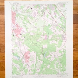 Puede incluir: Un mapa topográfico vintage de Pitman, East Woodbury y áreas circundantes en Nueva Jersey. El mapa está impreso en blanco y negro con acentos verdes y rosados. El mapa muestra carreteras, ríos y otras características geográficas.