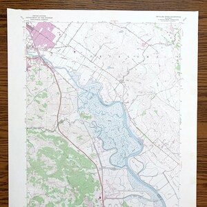 May include: A vintage map of the Petaluma River Quadrangle in California, showing the river winding through a green and brown landscape. The map is printed on paper and has a light blue tint. The map is titled "Petaluma River Quadrangle" and includes the text "United States Department of the Interior Geological Survey".