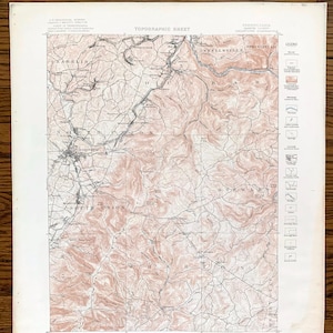 Op de afbeelding: Een vintage topografische kaart van het gebied rond Connellsville, Pennsylvania. De kaart toont het terrein, rivieren en wegen van de regio. De kaart is gedrukt in zwart-wit met bruine contourlijnen.
