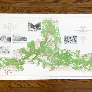 May include: A vintage map of the  Dinosaur National Monument in Colorado, USA. The map shows the park's boundaries, roads, trails, and points of interest. The map is printed on a white background with green and brown lines and text.