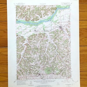 May include: A topographic map of the Blue Mounds, Wisconsin area, featuring a detailed depiction of the landscape. The map shows the Mississippi River in blue, with green and brown terrain, and various place names.