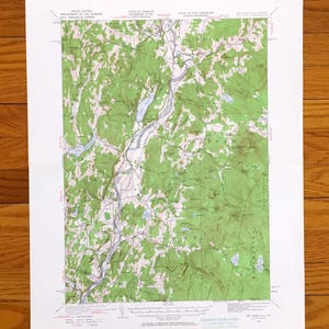 Può includere: Una mappa topografica degli Stati Uniti, con Vermont e New Hampshire. La mappa mostra un paesaggio dettagliato con aree verdi che rappresentano le foreste e un fiume. La mappa è stampata su carta bianca e misura in centimetri.