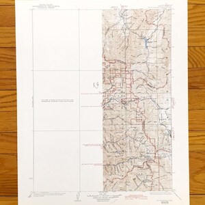 May include: A vintage topographic map from the United States Department of the Interior, Geological Survey. The map features detailed geographical information with contour lines, roads, and water bodies. The map is printed on white paper with brown and red ink.
