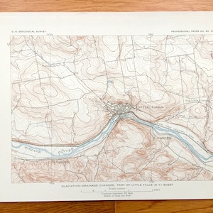 May include: A vintage map of Little Falls, New York, showing the Mohawk River and surrounding terrain. The map features contour lines, rivers, and other geographic features. The text "GLACIATION-DRAINAGE CHANGES, PART OF LITTLE FALLS N.Y. SHEET" is printed at the bottom of the map.