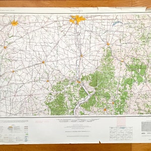 May include: A vintage map of Columbus, Ohio, with a network of roads and highways. The map features green shaded areas representing forests and yellow starbursts marking cities. The map is printed on aged paper.