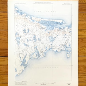 Può includere: Una mappa vintage di Cape Cod e Nantucket Sound, con lavaggi ad acquerello blu per i corpi idrici e dettagli del territorio. La mappa include nomi di luoghi e linee di griglia, stampata su carta invecchiata.