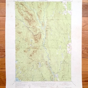 May include: A vintage topographic map of the Stacyville, Maine area. The map shows the location of roads, rivers, and other geographical features. The map is printed on cream-coloured paper and has a green and brown colour scheme.