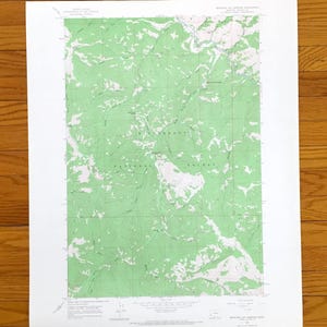 May include: A topographic map of the Bitterroot National Forest, featuring green and white shaded relief. The map includes contour lines and text indicating geographical features and the forest's name. The map is printed on white paper.