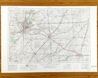 May include: A vintage topographic map of Peoria, Illinois, showing roads, rivers, and other geographical features. The map is printed on white paper and has a grid pattern.