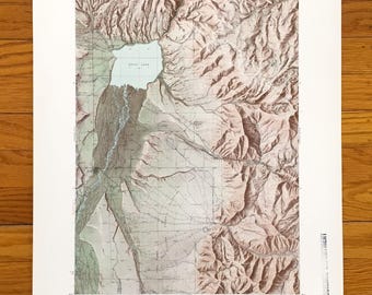 Puede incluir: Un mapa topográfico antiguo que presenta una representación detallada de una región montañosa con un gran lago. El mapa utiliza una paleta de colores beige, marrón y verde, con curvas de nivel que indican los cambios de elevación. El mapa está impreso en papel envejecido.
