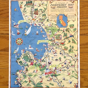 May include: A vintage map of the Monterey Bay Region, featuring Santa Cruz, Monterey, and Salinas. The map is illustrated with cartoon figures and landmarks, with text that reads "A Cartograph of Monterey Bay Region". The map is printed on a white background.
