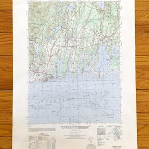Può includere: Una mappa topografica vintage di Falmouth, Massachusetts, con dettagli sulle caratteristiche del terreno, strade e corsi d'acqua. La mappa include il testo "Falmouth" e "Massachusetts 1:25.000". Stampata su carta invecchiata.