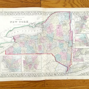 May include: Antique map of New York State, featuring detailed cartography with pink, blue, and green hues. The map includes insets of major cities and is framed by an ornate border. The title "State of New York" is prominently displayed.