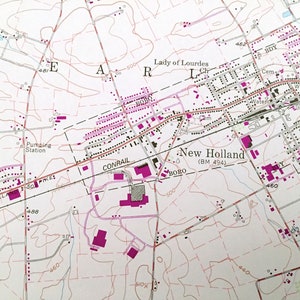 Op de afbeelding: Een zwart-witte kaart van New Holland, Pennsylvania, die de locatie van de Lady of Lourdes Church, een begraafplaats, een pompstation, een rioolwaterzuiveringsinstallatie en een spoorlijn laat zien. De kaart toont ook de locatie van verschillende wegen en straten.