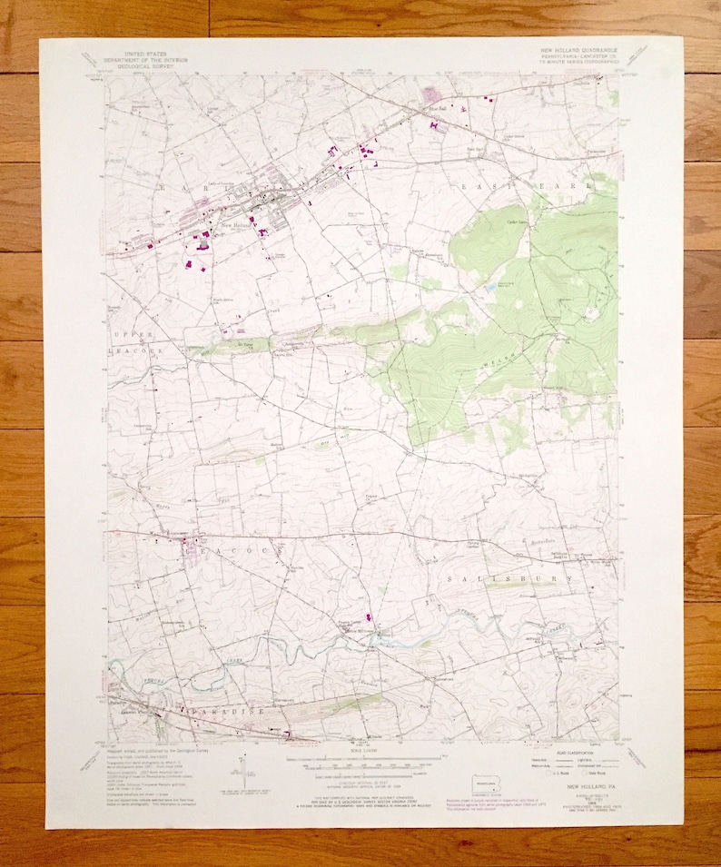 Op de afbeelding: Een vintage topografische kaart van New Holland, Pennsylvania, met wegen, rivieren en hoogtelijnen. De kaart is gedrukt op wit papier met zwarte lijnen en tekst. De kaart heeft de titel "New Holland Quadrangle" en bevat een schaalbalk en een legenda.