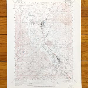 May include: A vintage topographic map, featuring detailed contour lines, roads, and geographical features. The map is printed on aged paper, with a faded color palette of beige, brown, and red, and is likely a historical document.