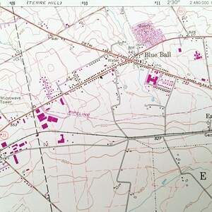Op de afbeelding: Een zwart-witte kaart met roze en rode markeringen. De kaart toont een stad genaamd "Blue Ball" met wegen, gebouwen en een pijpleiding. De kaart toont ook een "Microwave Tower" en een "Trailer Park".