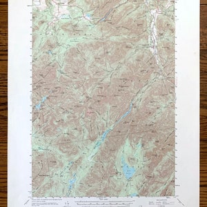 May include: A detailed topographic map of Mount Marcy, NY, from the United States Department of the Interior. The map features contour lines, bodies of water, and place names, printed in shades of brown, green, and blue. The map is on a white background.