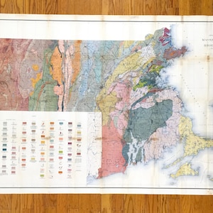 Può includere: Una mappa geologica vintage del Massachusetts e del Rhode Island, che mostra diverse aree colorate che rappresentano varie formazioni rocciose. La mappa include una legenda con una chiave per i diversi tipi di rocce.