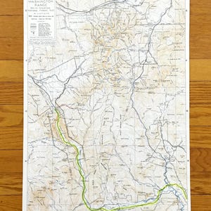 May include: A detailed map of the Mount Washington Range in White Mountain National Forest, NH. The map features contour lines, roads, and trails, with a highlighted green trail. The map is printed on a white paper.