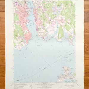 May include: A vintage map of New London, Connecticut, showing the city's streets, waterways, and surrounding areas. The map is printed on a light beige paper with blue and green lines and text. The map is titled "New London Quadrangle 1:24,000"