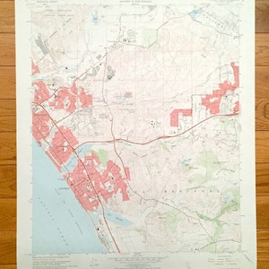 Puede incluir: Un mapa topográfico antiguo del cuadrángulo de San Luis Rey, California, con áreas costeras, carreteras y desarrollo urbano en rojo. El mapa incluye texto que indica el Departamento del Interior de EE. UU. y el Estado de California.