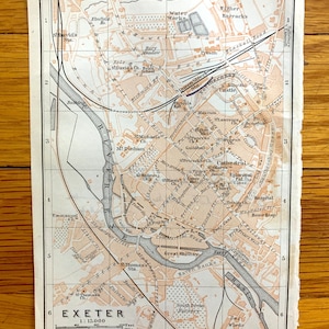 Peut inclure: Une carte vintage d'Exeter, en Angleterre, à l'échelle 1:15 000. La carte montre les rues, les bâtiments et les monuments de la ville, notamment la cathédrale, la rivière Exe et les lignes de chemin de fer. La carte est imprimée en encre brune et noire sur fond blanc.