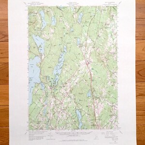 May include: A vintage topographic map of New Gloucester, Maine, showing roads, rivers, lakes, and elevation contours. The map is printed on white paper with green and brown lines and text.