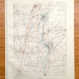Puede incluir: Un mapa vintage de Springfield, Massachusetts, que muestra las ciudades y los ríos circundantes. El mapa está impreso en blanco y negro con acentos azules y marrones. El mapa está titulado "Massachusetts - Connecticut, Springfield Sheet."