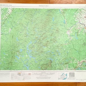 May include: A vintage map of Presque Isle, Maine, printed on a white background with green and blue markings. The map shows the area's topography, including rivers, lakes, and forests. The map is titled "Presque Isle" and includes a scale and legend.