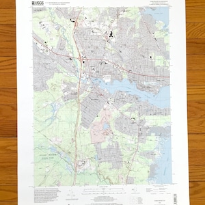May include: A USGS Toms River Quadrangle topographic map of New Jersey, printed on white paper. The map features detailed cartographic lines, red highway routes, blue water bodies, and green shaded areas representing parks and wooded terrain.