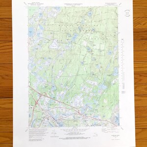 Puede incluir: Un mapa topográfico detallado con curvas de nivel, masas de agua y carreteras. Impreso en papel blanco, incluye texto que indica el origen y la escala del mapa. Un mapa antiguo.