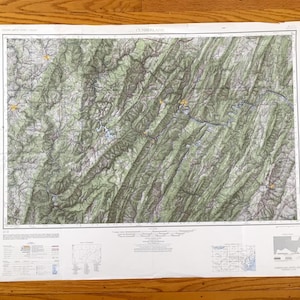 Puede incluir: Un mapa topográfico detallado del área de Cumberland, con relieve sombreado y curvas de nivel. El mapa está impreso en papel envejecido e incluye varios símbolos y leyendas. El mapa se muestra sobre una superficie de madera.