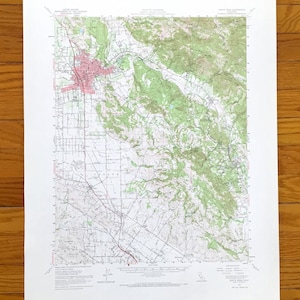May include: A detailed topographic map of Santa Rosa, California, featuring a red-shaded urban area, green-shaded hills, and a network of roads and trails. The map is printed on white paper and includes text indicating the map's title and scale.