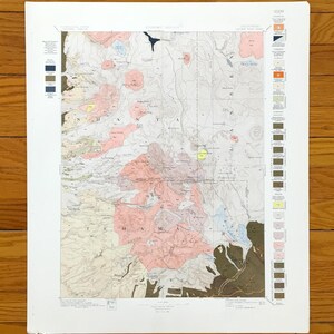 Puede incluir: Un mapa topográfico antiguo con una representación detallada del paisaje. El mapa presenta varios colores, incluyendo rosa, marrón y azul, para representar diferentes características geográficas. El mapa está enmarcado con un borde blanco e incluye una leyenda.