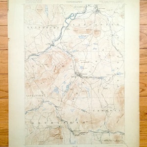 Puede incluir: Un mapa antiguo de la zona fronteriza de New Hampshire y Vermont, que muestra las ciudades de Lunenburg, Lancaster, Dalton, Littleton, Bethlehem y Carroll. El mapa está impreso en papel color crema y presenta líneas de contorno marrones, ríos y lagos azules y texto negro.