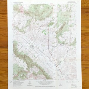 Può includere: Una carta topografica del United States Geological Survey del quadrilatero di Murrieta in California. La mappa presenta curve di livello dettagliate, terreno ombreggiato in verde, strade ed etichette di testo che indicano luoghi.
