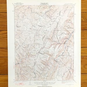 Puede incluir: Un mapa topográfico vintage del área de Forest, Wyoming. El mapa muestra la ubicación de montañas, ríos y carreteras. El mapa está impreso en papel color crema con tinta marrón y negra.