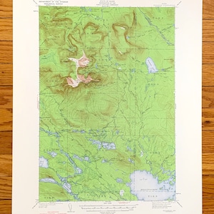 May include: A vintage topographic map of Maine, showing Mount Katahdin and surrounding areas. The map, printed on aged paper, displays contour lines, bodies of water, and place names. The map includes text from the United States Department of the Interior and the State of Maine.