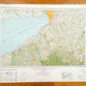 Pode incluir: Um mapa vintage de Buffalo, Nova Iorque, com uma área destacada em amarelo mostrando os limites da cidade. O mapa mostra a área circundante, incluindo o Lago Erie, e apresenta uma rede rodoviária detalhada.