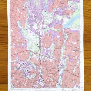 May include: A detailed topographic map of the Hackensack Quadrangle, New Jersey, showing roads, buildings, and natural features. The map uses a colour-coded system with pink, purple, green, and blue. The map is printed on white paper. Measurements are in inches.