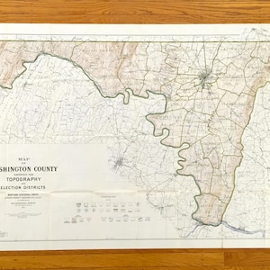 Puede incluir: Un mapa antiguo del condado de Washington, que muestra la topografía y los distritos electorales. El mapa presenta líneas detalladas, áreas sombreadas y texto, incluido el título "Map of Washington County". El mapa está impreso en papel envejecido.