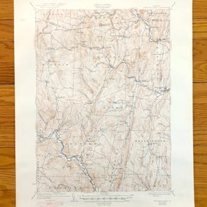 以下が含まれることがあります： 詳細な等高線、川、地名が特徴の、田園地帯のヴィンテージ地形図。 地図はセピア色のカラーパレットで、地形の標高と地理的特徴を示しています。 古紙に印刷されています。