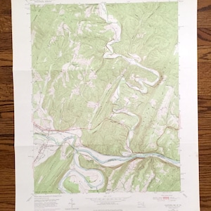 Puede incluir: Un mapa topográfico vintage de la zona de Gladetown, Virginia Occidental. El mapa muestra el terreno, los ríos y las carreteras de la zona. El mapa está impreso en papel y tiene una combinación de colores verde y marrón.