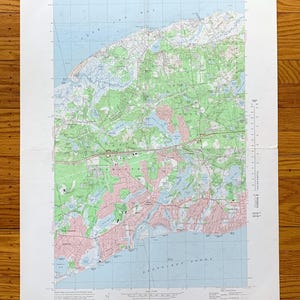 Puede incluir: Un mapa topográfico vintage del área alrededor de la ciudad de Smithtown, Nueva York. El mapa muestra carreteras, ríos y otras características geográficas. El mapa está impreso en un fondo azul claro con acentos verdes y rosados.