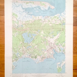 Puede incluir: Un mapa vintage de la zona de la isla de Nantucket en Massachusetts. El mapa muestra la costa, las carreteras y las ciudades. El mapa está impreso en papel marrón claro con marcas azules y verdes.