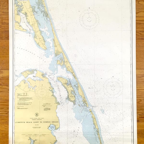 Può includere: Una carta nautica dell'area di Currituck Beach Light a Wimple Shoals nella Carolina del Nord. La carta è stampata su uno sfondo bianco con segni blu e gialli. La carta mostra la costa, gli ingressi e le secche. La carta è intitolata "Currituck Beach Light to Wimple Shoals".