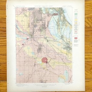 Pode incluir: Um mapa geológico vintage, "Economic Geology Sheet", apresentando um estudo geológico detalhado com várias cores e padrões. O mapa inclui texto, uma legenda e uma estrutura em grade, mostrando características geográficas.