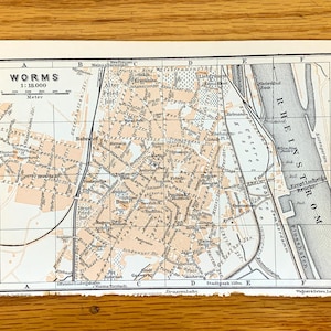 Könnte beinhalten: Eine Vintage-Karte von Worms, Deutschland, mit dem Titel "WORMS 1:18.000" und einer Skala in Metern. Die Karte zeigt die Straßen, Gebäude und Sehenswürdigkeiten der Stadt, einschließlich des Rheins.